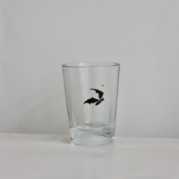 Fledermaus, Gravur auf Glas mit schwarzer Farbe eingelegt, darüber ein kleines goldenes Krönchen.